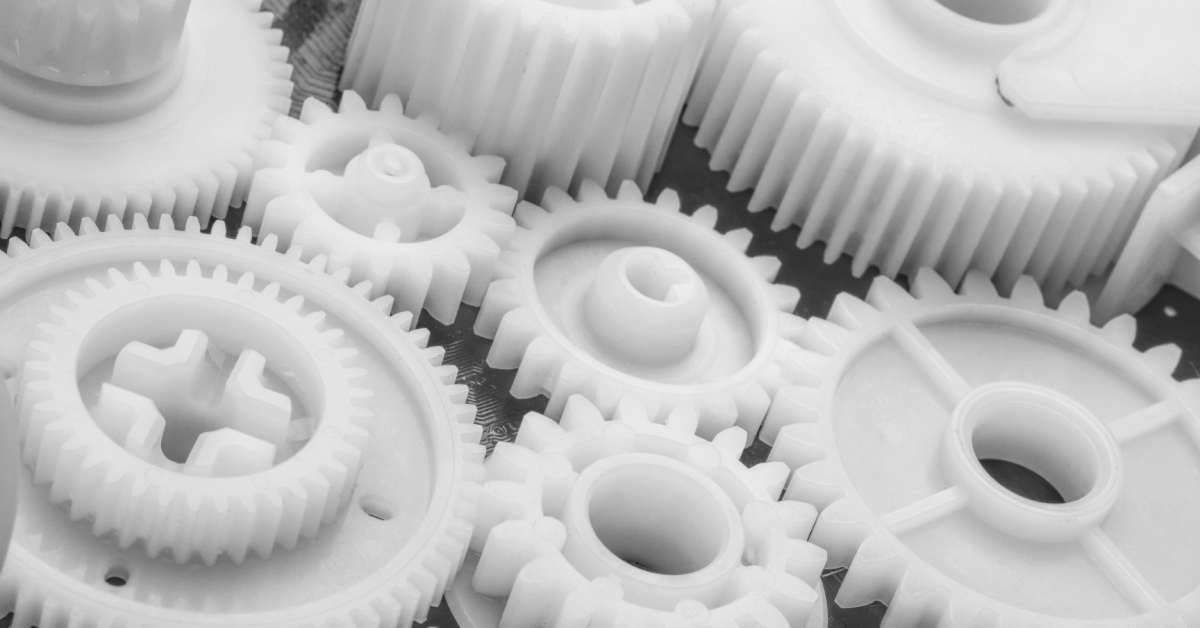  Plastic gears that are neatly arranged together. The plastic gears are colored white and are lying on a surface.